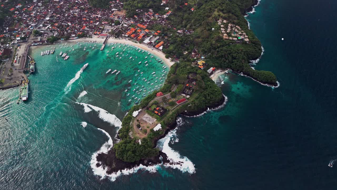 Aerial view of Padang bai Harbor showcasing turquoise waters, anchored boats, and surrounding lush coastline, capturing the vibrant gateway connecting Bali with Lombok and the Gili Islands