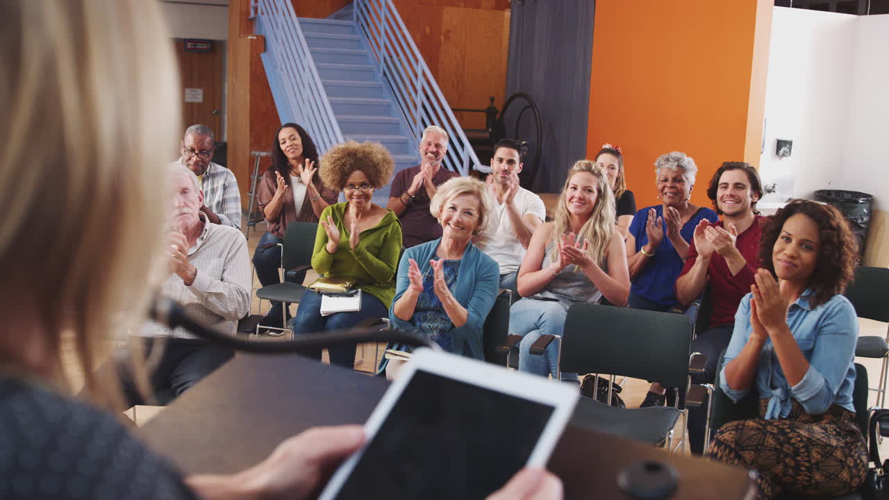 이웃 모임 에 참석 한 그룹 이 커뮤니티 센터 에서 연설자 를 박수 를 치고 있다