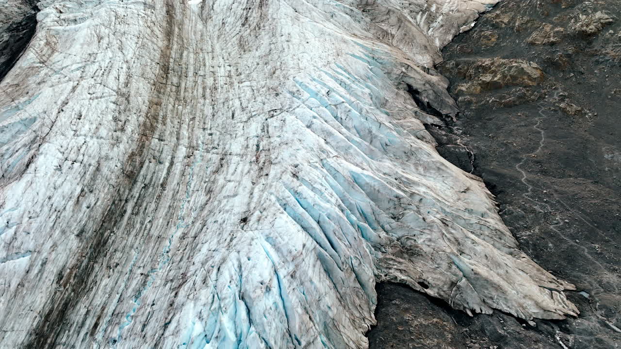 Glacier covering the bare rocks. Drone flight over the ice in the mountains of Alaska, USA