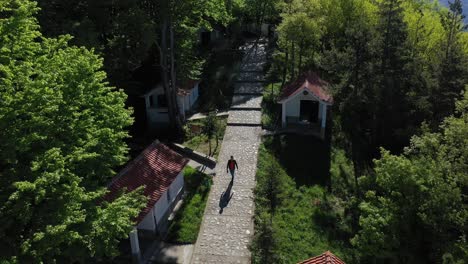 man walking between chapes on a path di cruciferous forest