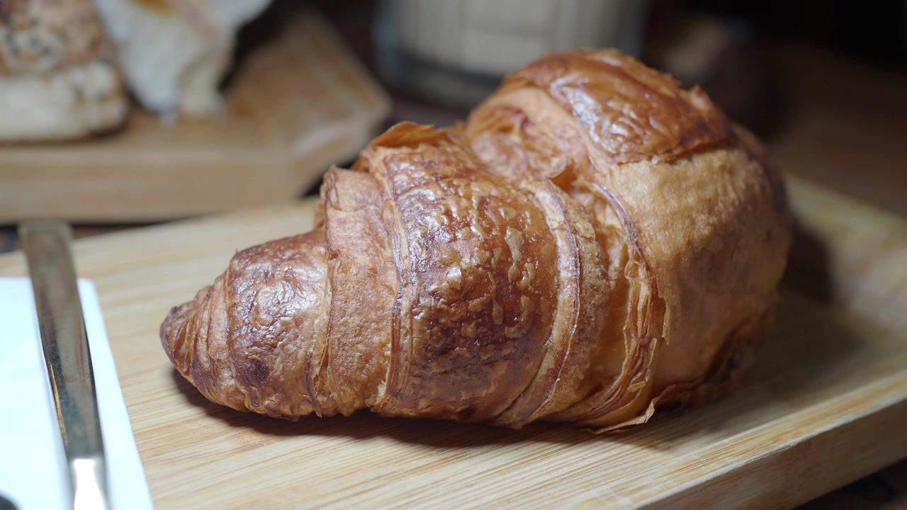 Close-up of a Freshly Baked Golden Croissant on a Wooden Tray