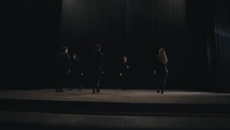 side view of five confident student actors in the theater walking on stage during their rehearsal and preparation for classes at the theater university