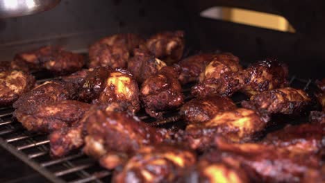 primer plano: salsa barbacoa cepillada sobre alitas de pollo y muslos asados