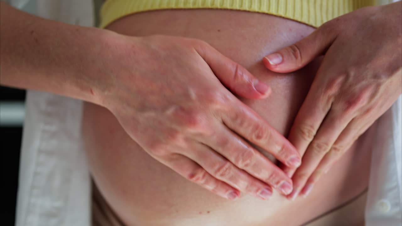 Primo piano di una donna che si massaggia la pancia con l'olio durante la gravidanza