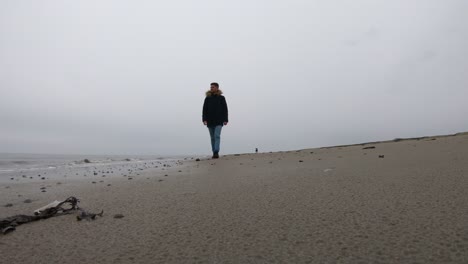 man walking alone on the beach on a rainy day