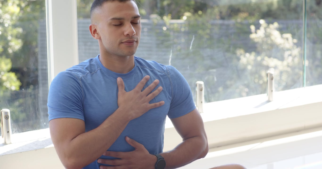 Uomini afroamericani che respirano con le mani sul petto su un tappetino mentre la telecamera si muove lentamente per un effetto di calma, con spazio per il testo.