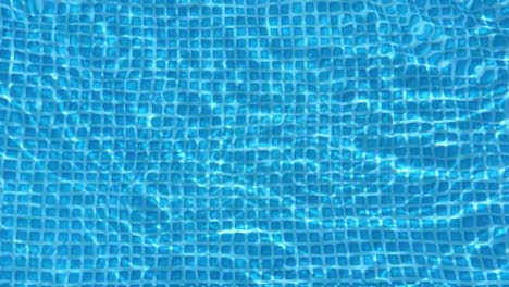 light reflecting and refracting on the rippling surface of a swimming pool creates a mesmerizing pattern on the blue tiles below, perfect for summer-themed projects
