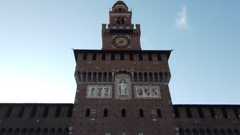 the sforza castle ancient fortress in milan city center, tilt up front view of the main gate facade with italian flag and symbol of the old city