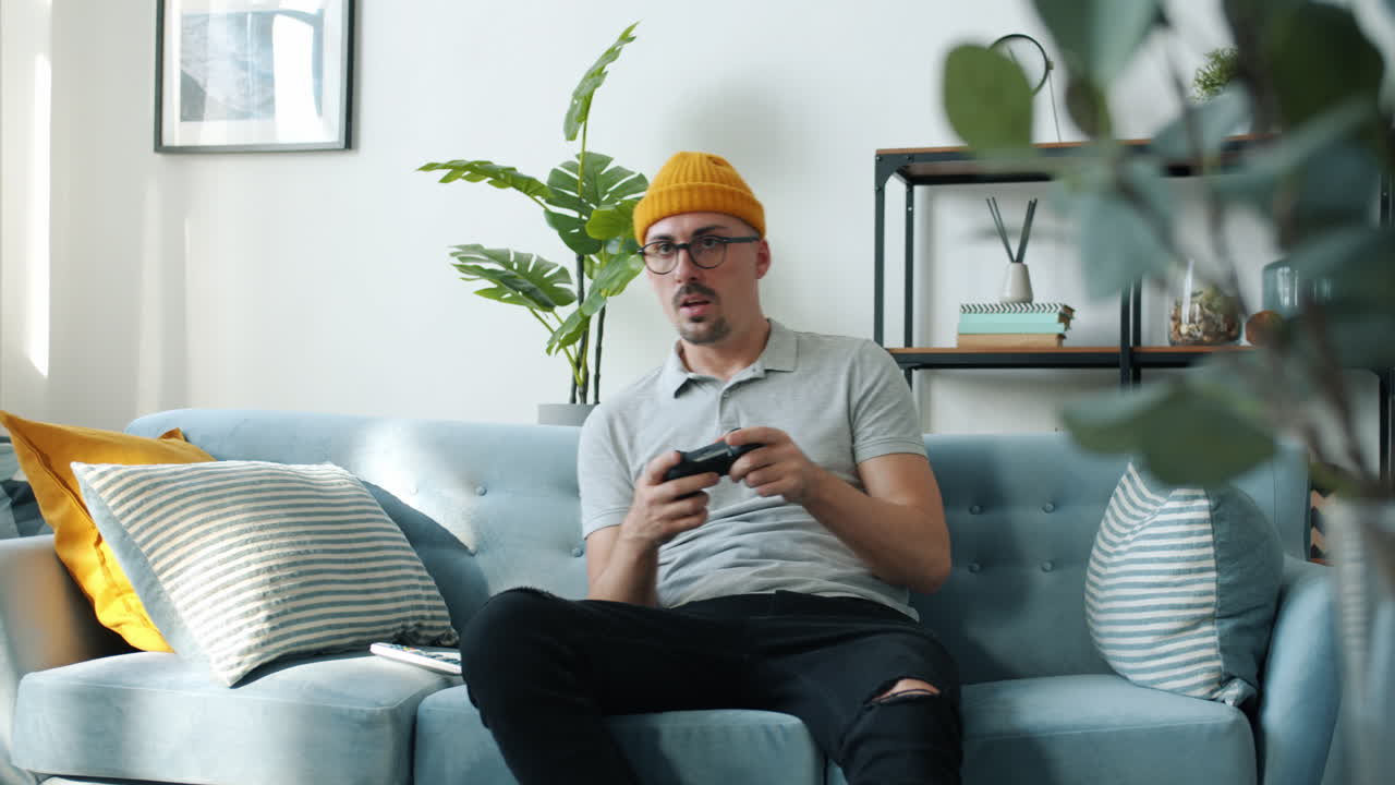 Uomo che gioca a videogiochi sul divano