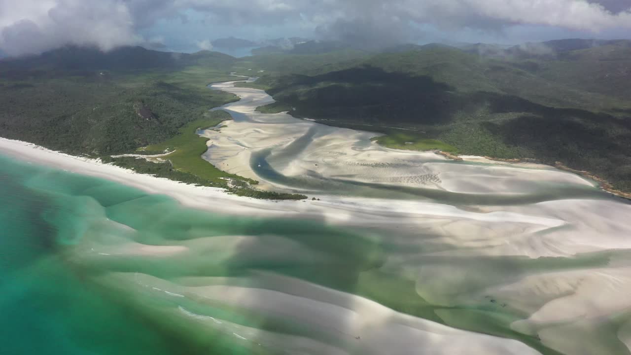 Una barca a vela solitaria risale un'insenatura fluviale poco profonda nel Parco delle Isole Whitsunday.
