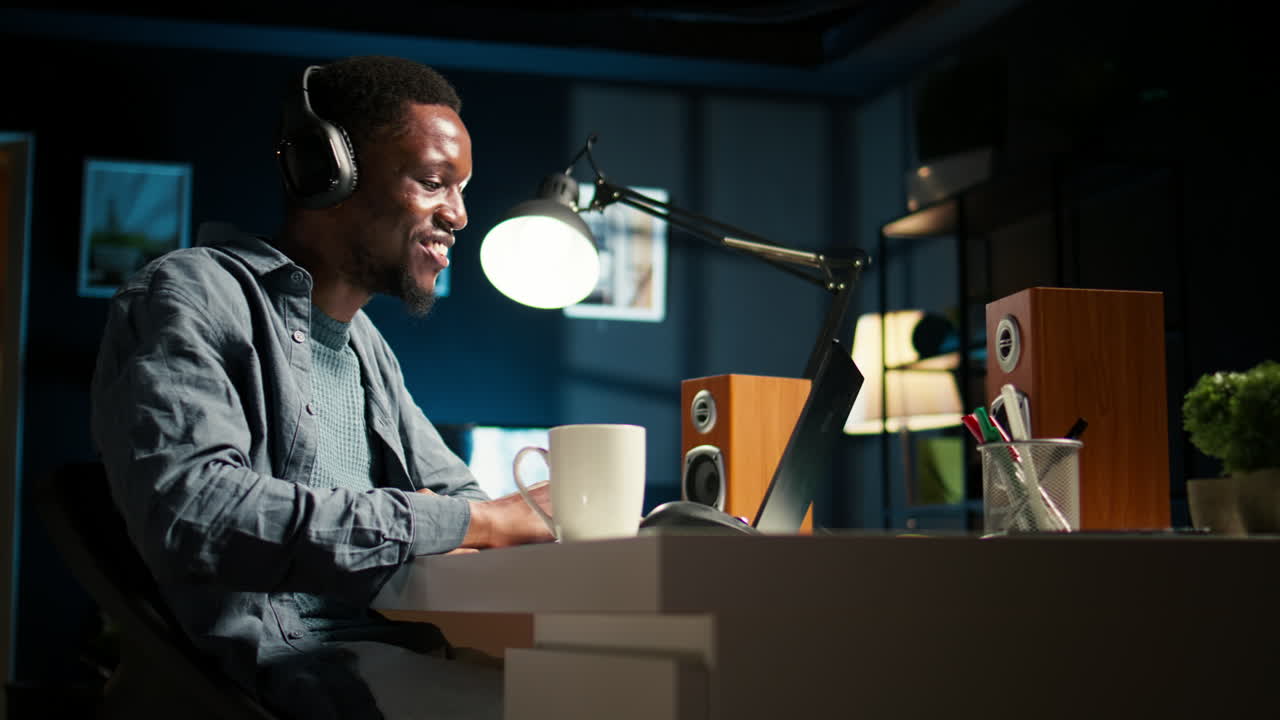 Young focused freelancer attending an online meeting from his home office