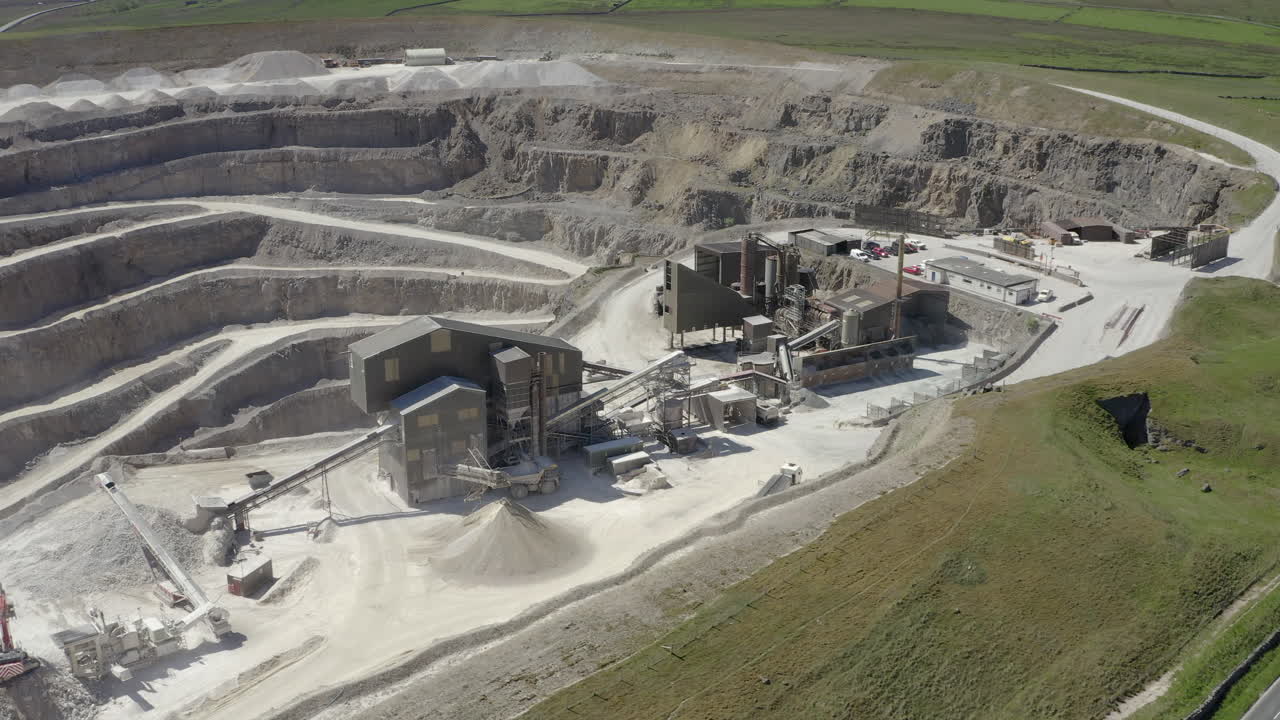 An aerial view of a working asphalt quarry building with the quarry cut in the background, Yorkshire, UK