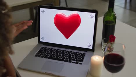 Animation-of-heart-over-african-american-woman-drinking-wine-and-using-laptop-with-copy-space