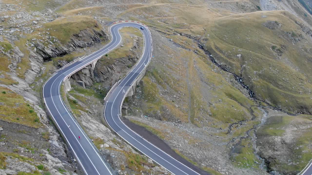 vista aérea de dos corredores corriendo por una carretera en la montaña transfagarasan, rumania