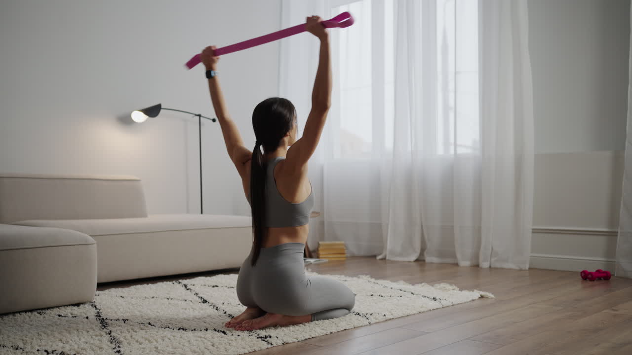 mujer estirándose con banda de resistencia en casa
