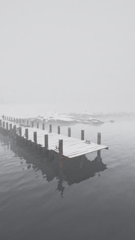 a wooden pier extends into a foggy lake