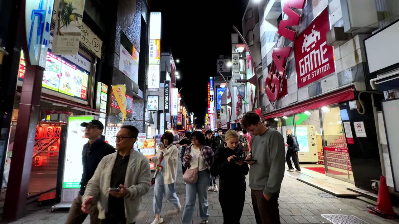 Bustling street in Tokyo's Ueno district at night with neon signs and busy storefronts