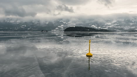 calm icy steinsfjorden in vik, norway with yellow lake buoy and reflections of clouds soaring above