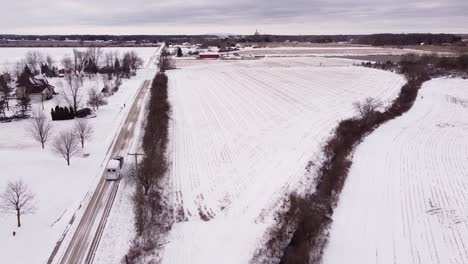 farmer haul white horse trailer on winter road in rural area of michigan, aerial shot