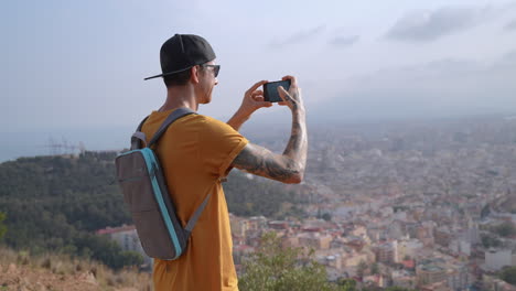 young men on mountain hike filming cityscape with smartphone camera