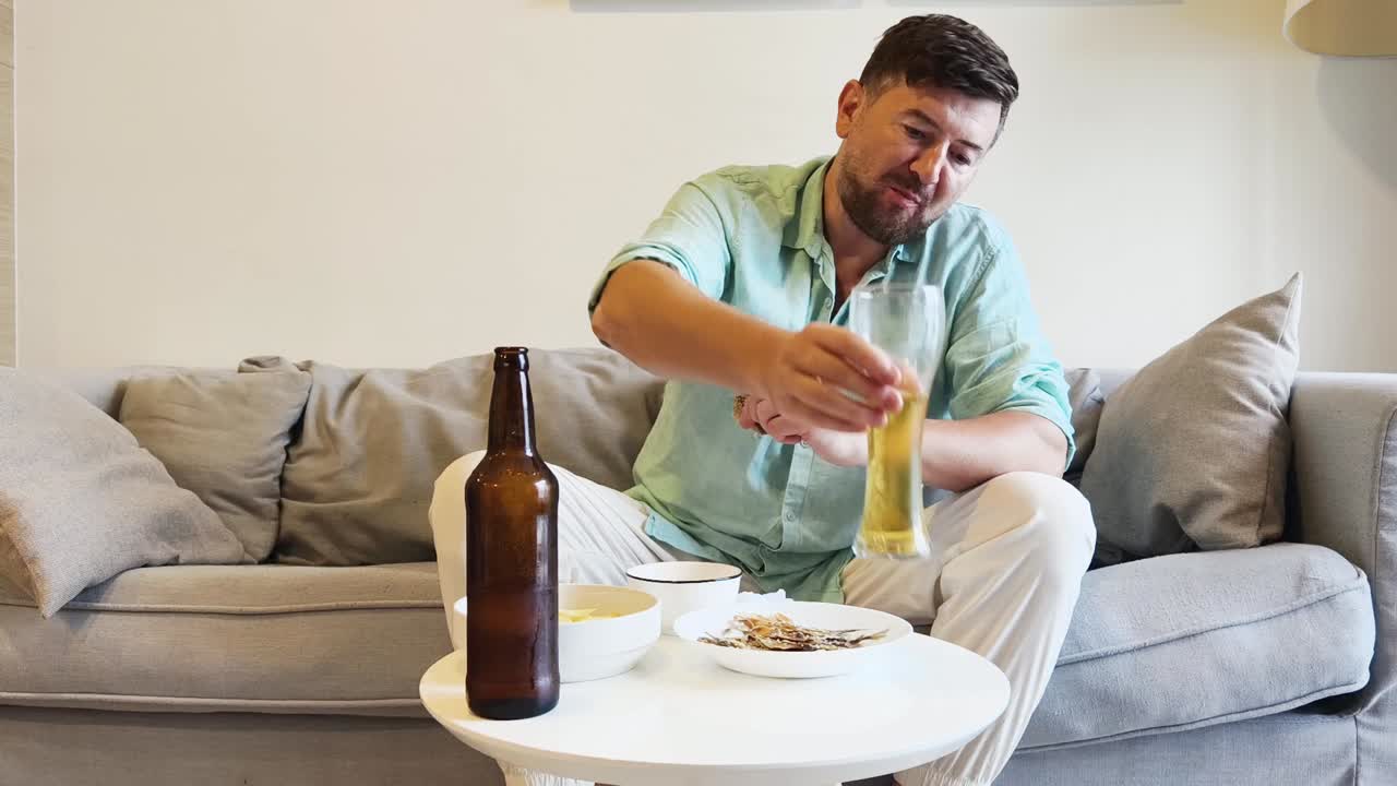 Man relaxing on couch with beer and snacks