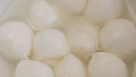 mozzarella cheese in bowl close-up. mozzarella is a semi-soft non-aged cheese prepared by the pasta filata method from italian cow's milk. mozzarella is used for most types of pizza and several pasta dishes or served with sliced tomatoes and basil in caprese salad.