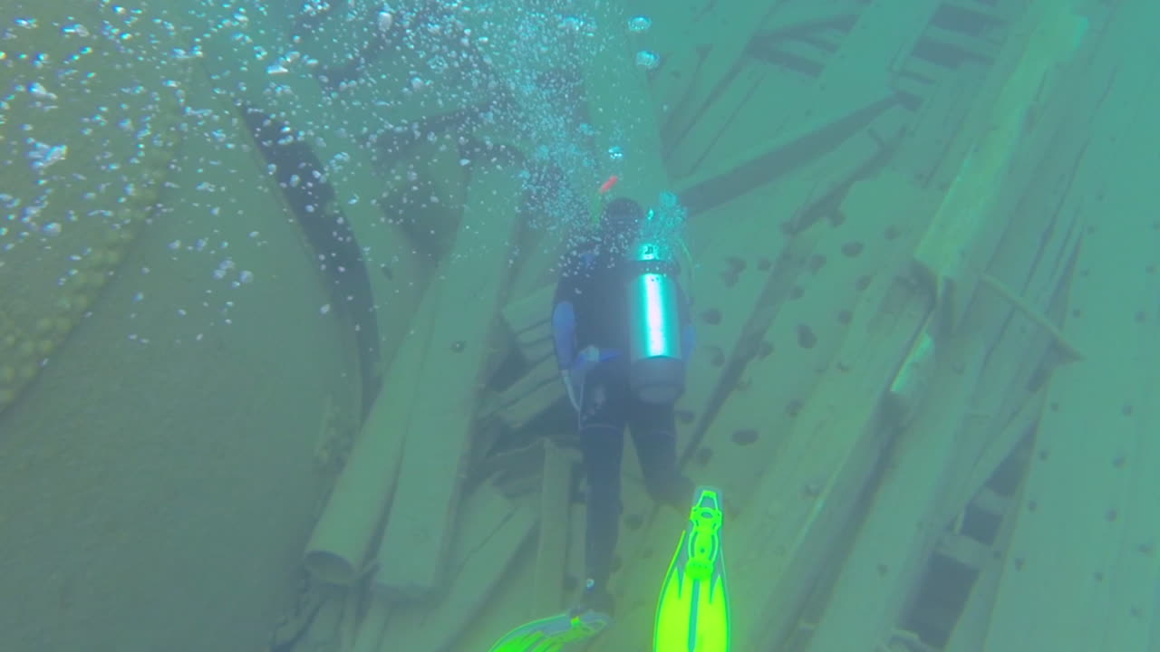 침몰한 배의 수중 잔해를 탐험하는 다이버를 따라가다