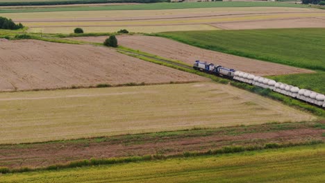 modern freight train with industrial cargo moves through rural poland, aerial view