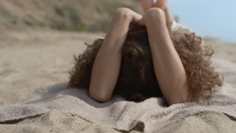 happy woman frolicing hiding smiling face close up. girl lying sand seashore.