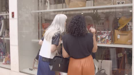 cheerful female friends standing at shop window