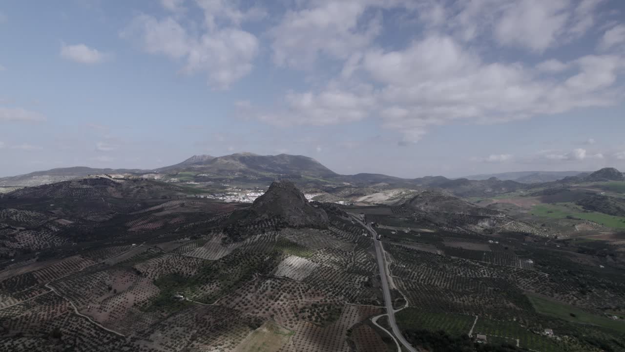 Aerial 4K footage of Olvera, Spain, captured with a DJI drone at 30fps. A cinematic view of open meadows with a stunning castle atop the mountain in the background.