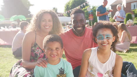 retrato en cámara lenta de una familia con niños sentados en una alfombra en una fiesta de jardín de verano