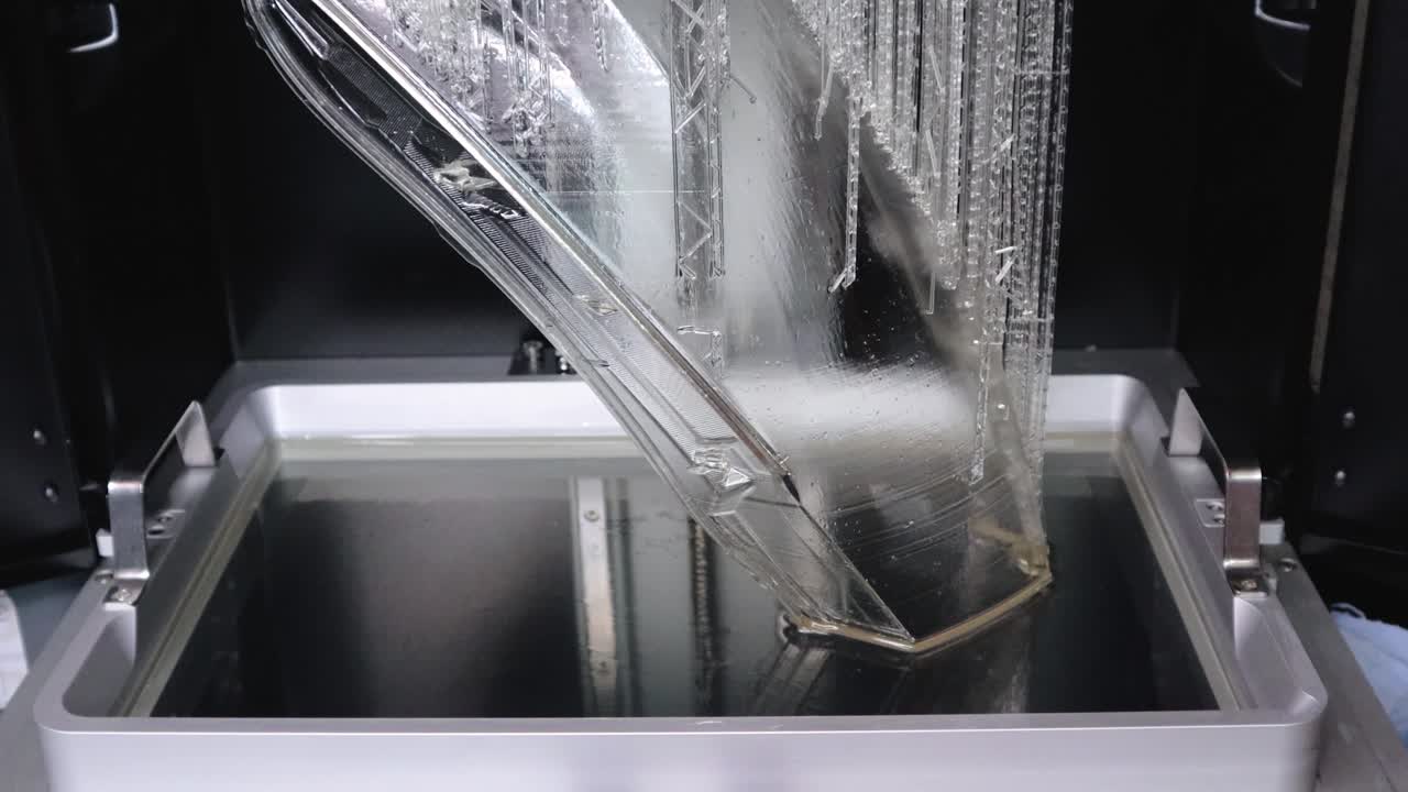 자동차의 풀 사이즈 헤드라이트 렌즈를 위한 최종 레이어를 생성하는 수지 3d 프린터의 빌드 챔버 가까이