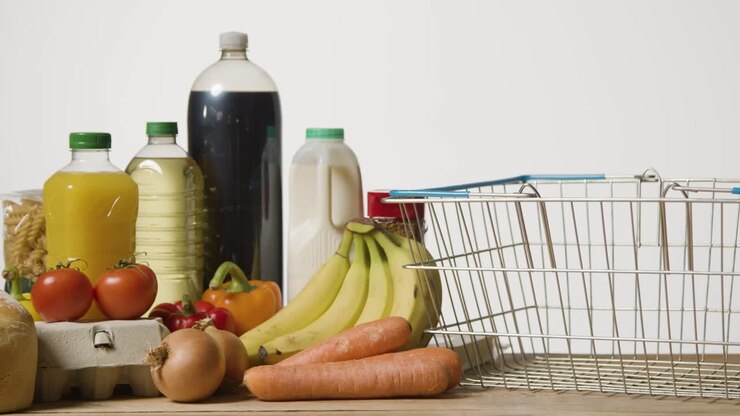 Studio Shot Of Basic Food Items Next To Supermarket Wire Shopping Basket 1