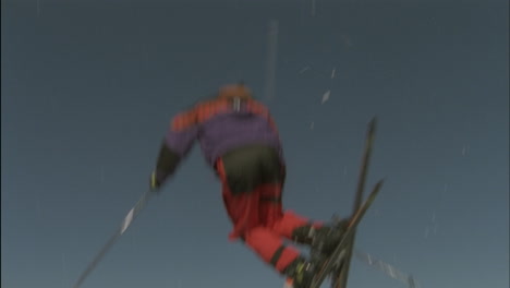 un esquiador salta y cae en la nieve