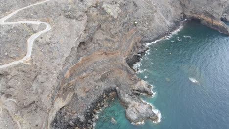 Luftbild-Von-Oben-Auf-Die-Felsige-Küste-Der-Kanarischen-Inseln-Mit-Wellen,-Die-Am-Ufer-Schwarzer-Sandstrände-Spritzen
