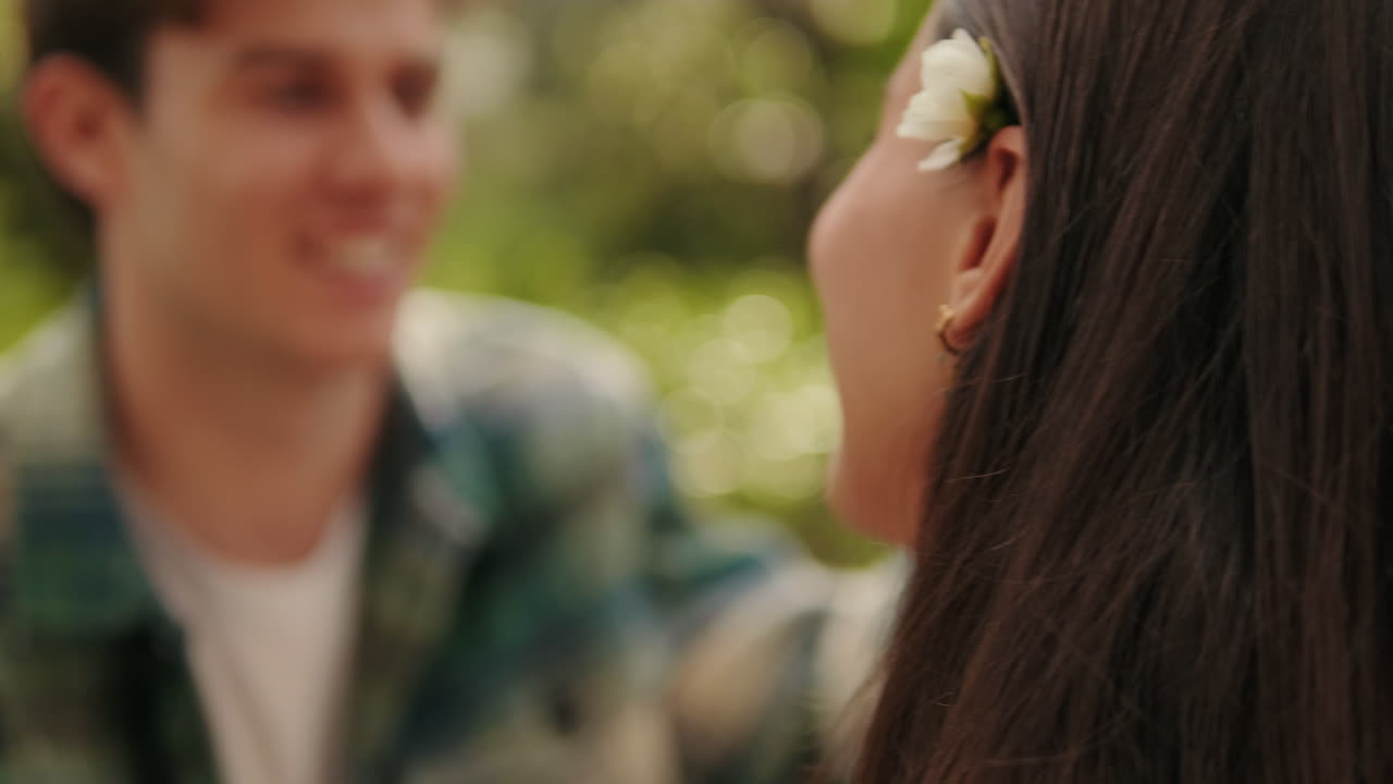 Close up young man putting flower behind his girlfriend's ear