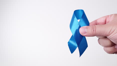 detail of male hand holding ribbon in light blue color on white background