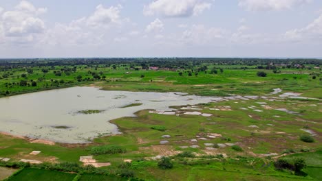 agricultural land with lake, greenery, and clouds at tekmal village, medak, telangana, india. day time, push in, drone shot, 4k.