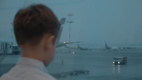 niño esperando un vuelo en el aeropuerto y viendo aviones