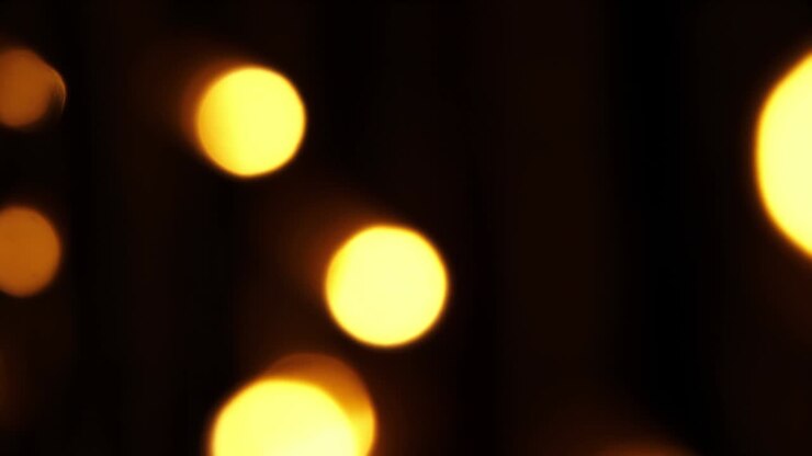 Abstract bokeh background in motion. shining, blurred golden particles, lights. bright bokeh from garlands on dark background. New year or Christmas festive backdrop