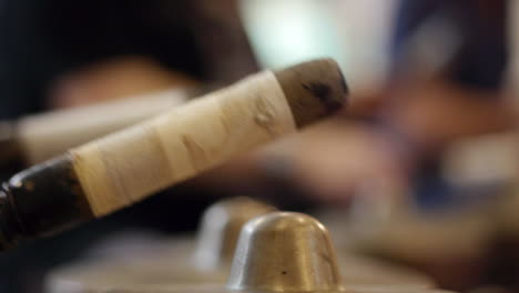 wooden mallet being used to strike multiple south east asian bonang drums during gamelan performance, filmed as extreme close up in handheld style