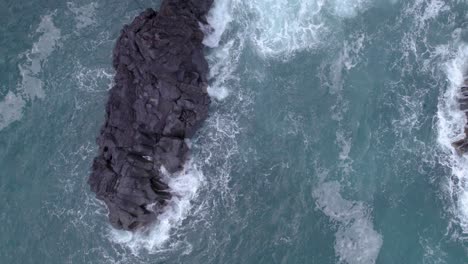 Aerial-top-down-shot-of-the-sea-waves-crashing-on-the-volcanic-cliff-in-Sicily,-Italy