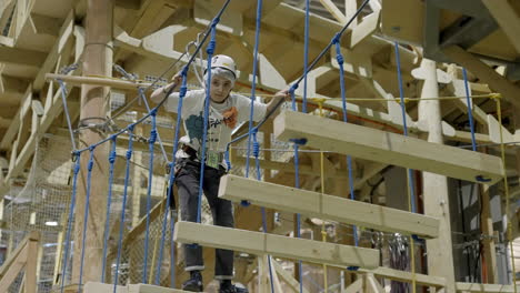a young person navigating an indoor rope course or adventure park