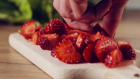 chopped strawberries on a wooden cutting board