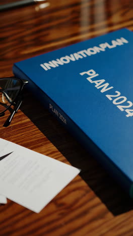 office desk with documents, glasses, and innovation plan 2024