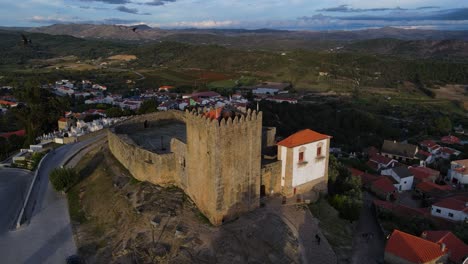 un dron captura una bandada de pájaros que vuelan más allá de la torre del castillo de belmonte mientras se ponen las puestas de sol