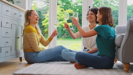 grupo de amigas relajándose en casa sentadas en el salón charlando celebrando con un vaso de vino