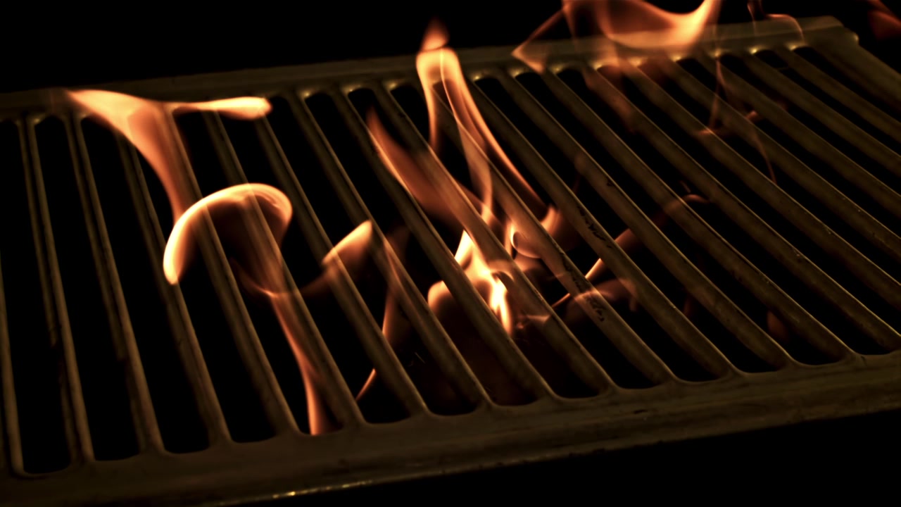 Fiamme ardenti che bruciano sotto una griglia vuota per barbecue