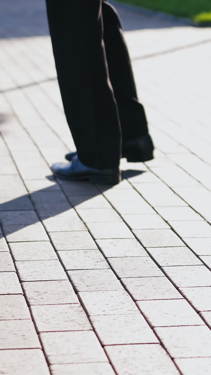 Feet of the businessman walking outdoors. Legs of a man in black trousers and shoes walking nervously up and down the street. Close-up. Vertical video